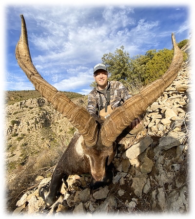 Hunter with his Beceite ibex hunting trophy on a mountain 